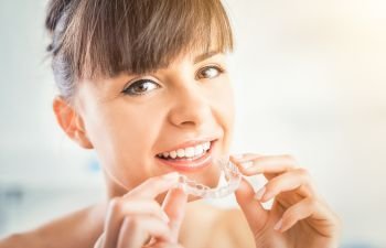 A woman removing clear dental aligner